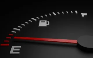 Close-up of a car fuel gauge with the needle pointing to empty, indicating the need for fuel delivery.