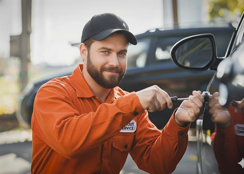 Lockout assistance service with a technician in an orange uniform unlocking a car door to help a stranded customer.