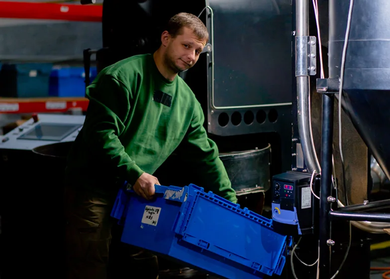 Equipment transfer service with a worker handling a blue container in an industrial setting.