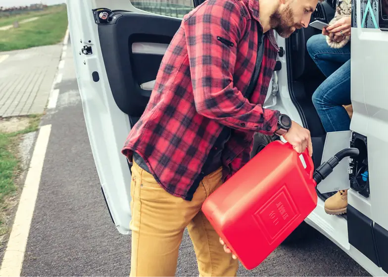 Emergency fuel service with a person pouring gasoline from a red fuel can into a vehicle on the side of the road.
