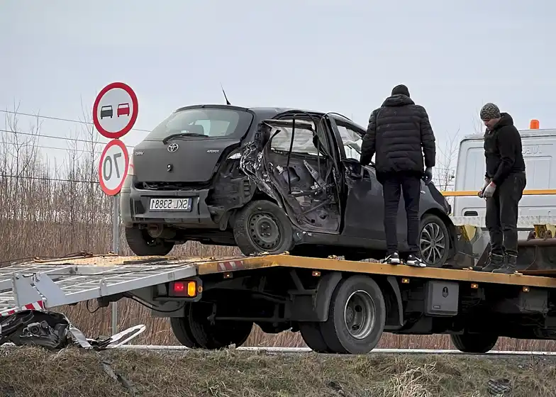 Flatbed towing service with a damaged car being loaded onto a tow truck after an accident on the roadside.